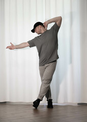 Dance in motion, pose of a man in hip-hop style clothes. Sports dancing guy in training poses. Dance training at home.