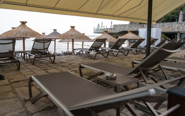Beach sunbeds, chairs on beach on seaside resort, coastal town leisure area, relaxation, empty coastal chairs