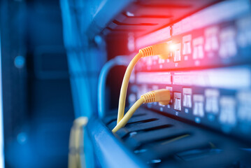 Fototapeta premium close up of network cables connected to server racks in data center room.