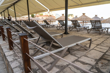 Beach sunbeds, chairs on beach on seaside resort, coastal town leisure area, relaxation, empty coastal chairs