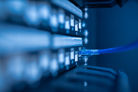 close up of network cables connected to server racks in data center room.