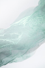 A close-up photograph of a light mint green ink swirl on a white background