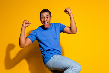 Photo portrait of attractive young man winning raise fists dressed stylish blue clothes isolated on...