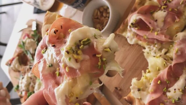 Hand golding hot slice of fresh Italian pizza . High quality vertical footage