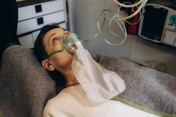 Ambulance car interior. Emergency medical service equipment. Patient on a stretcher receiving first aid. Close-up of screen of multiparameter patient monitor. Medical care and emergency transportation