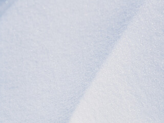 Obraz premium Beautiful winter background with snowy ground. Natural snow texture. Wind sculpted patterns on snow surface. Closeup top view with copy space.