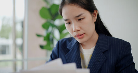 Portrait of Asian businesswoman in suit use digital tablet for work and analyze documents in small coffee shop. Work from anywhere, Remote working