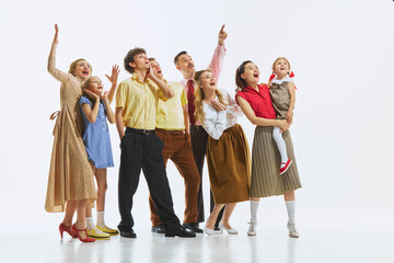 Fototapeta premium A group of people in vintage attire pointing and looking upwards with shock and excitement, isolated on white background. Announcement, event, discovery, news. Opening