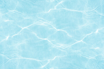 Blue water with ripples on the surface. Defocus blurred transparent blue colored clear calm water surface texture with splashes and bubbles. Water waves with shining pattern texture background.