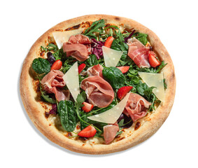 Appetizing pizza with browned crispy edges filled with creamy cheese sauce, thin slices of Italian prosciutto, mix of greens, slices of parmesan and ripe strawberries, isolated on white background