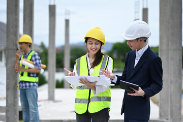 Fototapeta premium Construction professionals team and businessman in hard hats discussing on project at building site