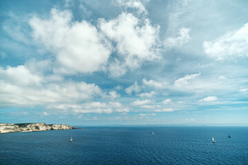 Yachts sailing past the limestone cliffs in the bay of Bonifacio on the south coast of Corsica with...