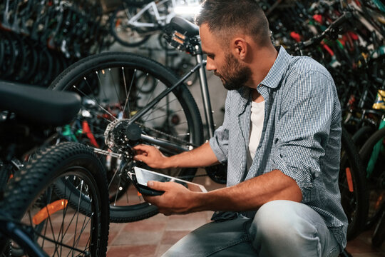Using digital tablet. Repair man in bicycle shop, working in store