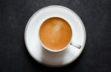 Top view of morning espresso coffee or black coffee in a white glass cup on a black table background 2024. Beautiful coffee cup with foam of Americano on black background.