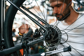 Cleaning the chain. Repair man in bicycle shop, working in store