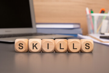 SKILLS wooden cubes with letters on a laptop keyboard with charts, business documents,