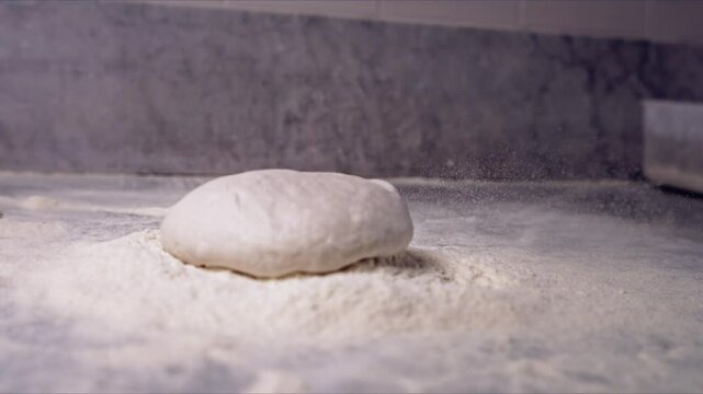 Pizza dough being throw to a table with flour
