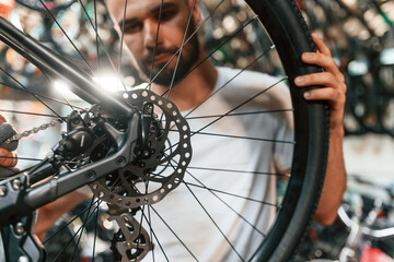 Rear wheel adjustment. Repair man in bicycle shop, working in store
