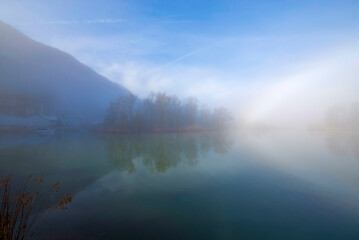 Fototapeta premium Alpine Lake Maggiore with Fog and Trees in Locarno, Ticino, Switzerland.