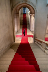 Woman Standing on a Red Carpet and Looking Up in an Old Building with Staircase in Switzerland.