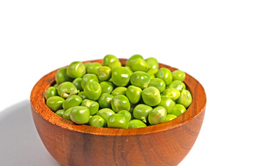 Grüne Erbsen in einem Holzschälchen vor weißem Hintergrund