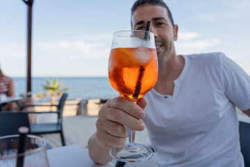Man holding spritz cocktail on beach terrace.Tourist is enjoying an spritz cocktail in a restaurant...