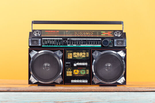 Retro outdated portable stereo boombox radio cassette recorder from 80s front yellow background. Vintage old style filtered photo