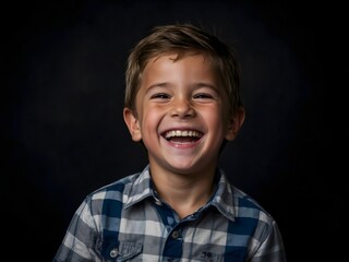 Portrait of a little boy laughing, black background with copy space