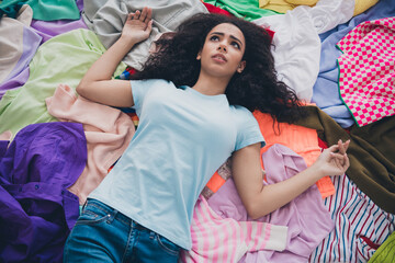 Above view photo of nice young girl lying messy clutter clothes think contemplate flat indoors