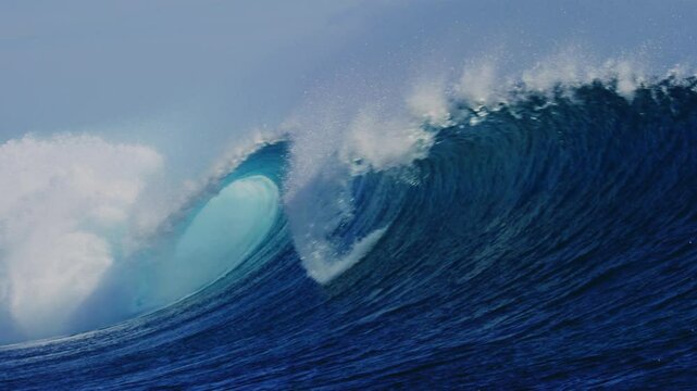 Perfecty empty blue wave barreling and crashing as ocean water sparkles in slow motion