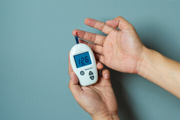 Woman's hands checking diabetes and hyperglycemia with digital blood sugar meter. Healthcare and...