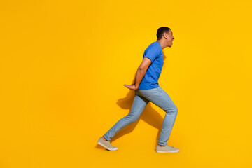 Full body photo of attractive young man hold carry back empty space dressed stylish blue clothes isolated on yellow color background