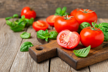 Fresh cherry tomatoes and fresh green basil on a textured background. Tomato sauce. Vegan. Ingredients for salad. Organic food. Place for text. Copy space.