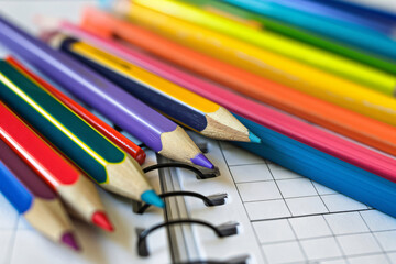 Obraz premium Vibrant colored pencils scattered on open notebook, ready for use. Spiral binding and blank pages offer endless possibilities for writing, drawing, planning