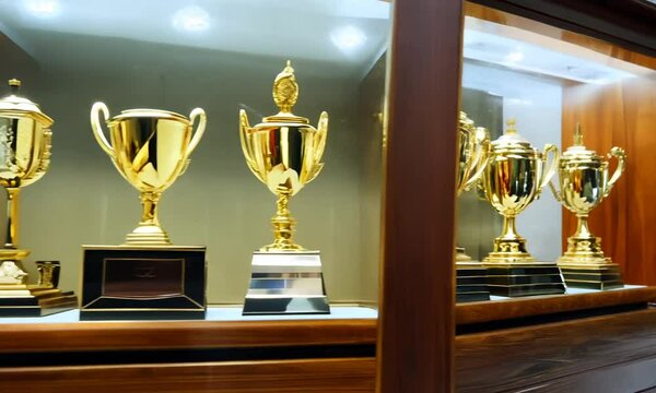A glass case made of wooden elements, filled with gold and silver trophies.