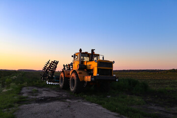 Cultivator on agricultural field at golden hour. Machine in field at sunset.
