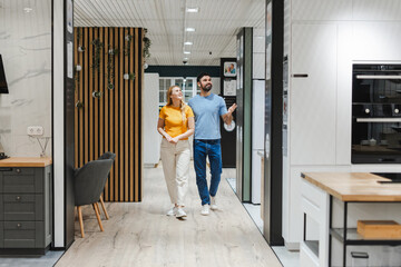 Smiling young couple walking in the furniture section in large furniture store