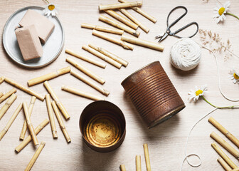 Top view of workplace with two old empty rusty food cans, bamboo stakes, air dry clay, string, scissors. Create a DIY bug hotel for garden. Kids craft and helping wild animals concept.