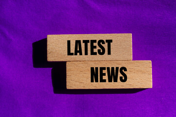 Latest news message written on wooden blocks with purple background. Conceptual latest news symbol....
