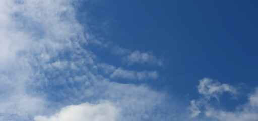 Fototapeta premium A serene photograph of the sky with fluffy clouds, capturing the peacefulness and beauty of nature. The image showcases the various shapes and textures of the clouds against a vibrant blue sky, evokin