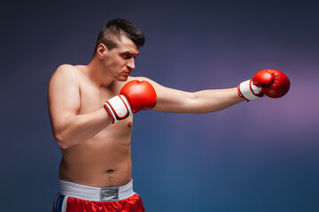 Muscular boxer throwing a punch wearing red boxing gloves