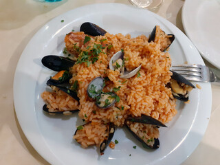 Bari Sardo, Nuoro, Sardinia, Italy, 2 July 2024: an excellent dish of fisherman's rice garnished with mussels, prawns and other seafood, tomato sauce, oil and spices