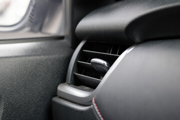 A black car interior with a black air vent