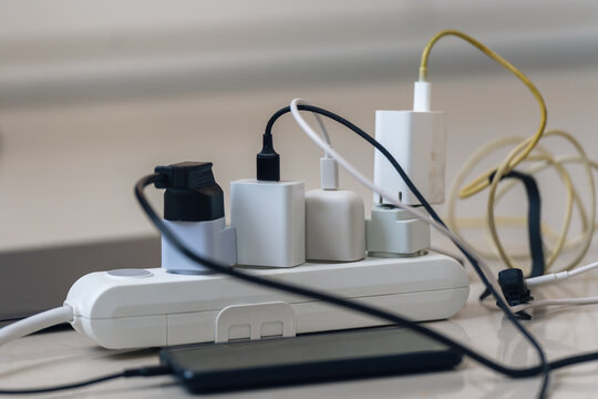 Electrical outlet with many chargers connected to it for a smartphone, laptop, microphone