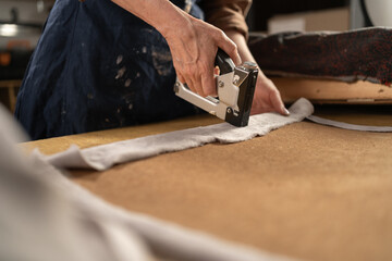 Female carpenter using pneumatic stapler after replace upholstery fabric to the Seat for armchair....
