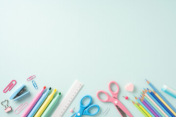 Top view of various school stationery items arranged on a light blue background, perfect for back-to-school themes