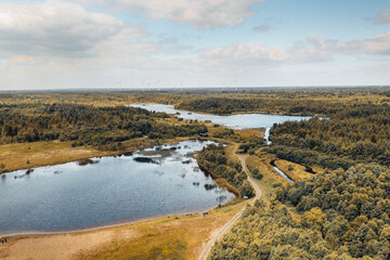 Aerial view of Derryounce Lakes featuring tranquil waters, lush greenery, and winding trails. The landscape includes wind turbines in the distance, highlighting the area's natural beauty.