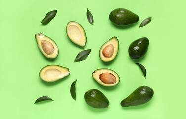 Fresh ripe avocados and leaves on green background