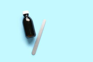 Cough syrup with tongue depressor on blue background