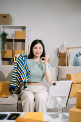 Fashion blogger concept, Young Asian women selling clothes on video streaming.Startup small business SME, using smartphone or tablet taking receive and checking.